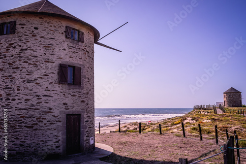 Two windmills on the dunes of Apúlia beach with a wooden fence and cordon delineating the walkway, Esposende PORTUGAL