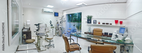 Clinica Oftamologista com cadeira mesa de vidro e equipamentos photo