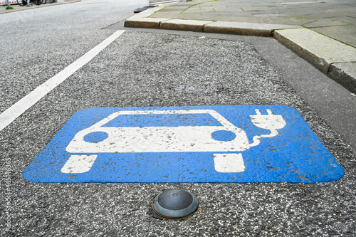 Electric car charging symbol on street. Parking sign on asphalt in city. Hybrid and electric cars can be charged here. Charging station symbol. 