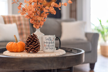 Coffee table with a mug that says Talk Pumpkin Spice to Me in a stylish living room decorated for fall