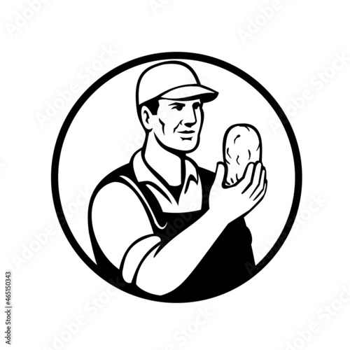 Mascot illustration of an organic farmer or potato grower holding up a potato viewed from front set inside circle on isolated background black and white retro style.
