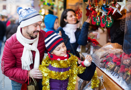 Family with children choosing decoration and souvenirs at Christmas market