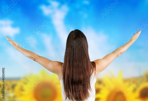 Sunny beautiful picture of young cheerful girl holding hands up and looking at sunrise