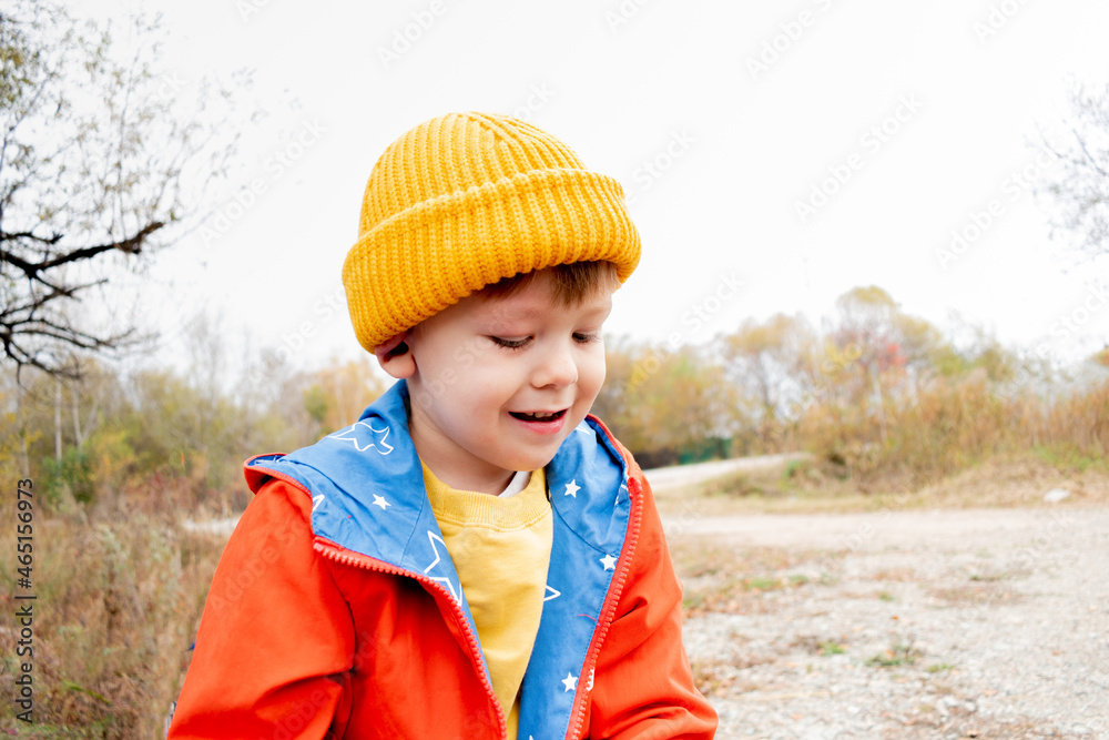 Boy in an orange jacket rides a balance bike in the autumn forest. Copy space Boy in an orange jacket rides a balance bike in the autumn forest. Copy space