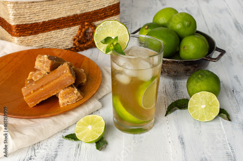 View from above of a glass of cold panela drink or sugarcane water with lemon and fresh ice, homemade on an aged wooden table photo