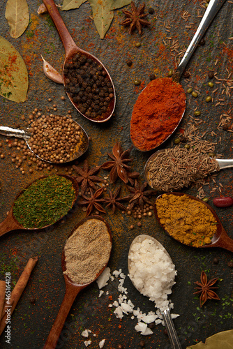 spices concept various colors and types of spices sorted into spoons, and some being sprinkled on the black background