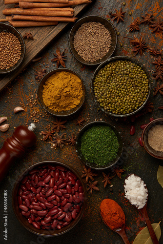spices concept many colors and types of spices placed into spoons and small bowls, and some being sprinkled on the black background with other devices © snowing12