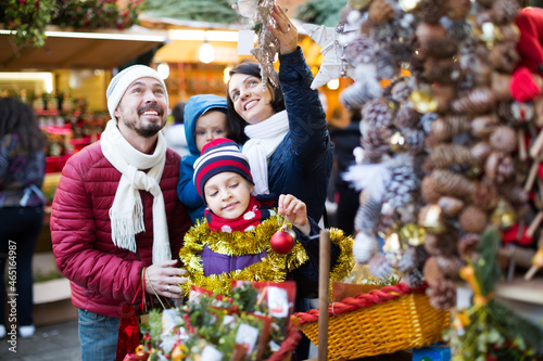 Smiling family with children purchasing Christmas decoration and souvenirs at fair
