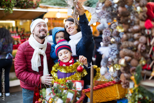 Smiling family with children purchasing Christmas decoration and souvenirs at fair © JackF