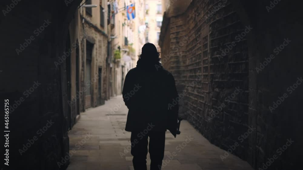 Young man walks and skates in old alleyway arch, Barcelona Slow motion Young man walks and skates in old alleyway arch, Barcelona Slow motion