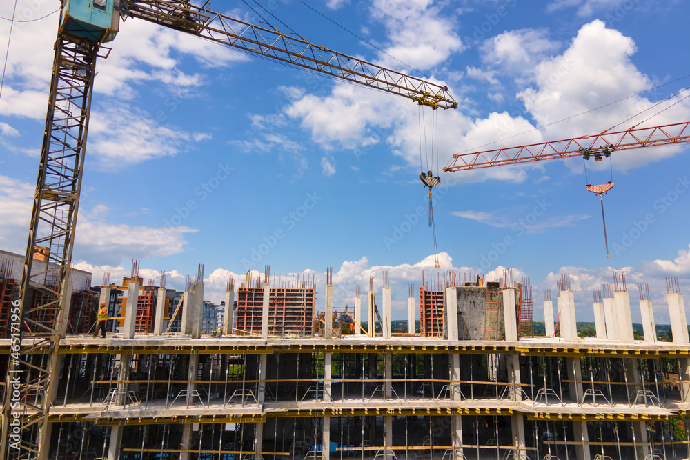 Tower crane at high concrete residential building under construction. Real estate development concept.