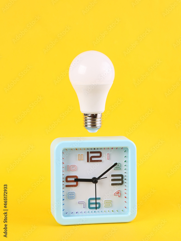 Alarm clock with floating light bulb on yellow background. Minimal idea,  inspiration concept Stock Photo | Adobe Stock