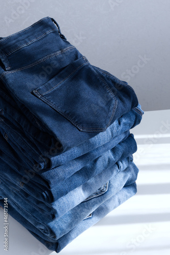 a pile of blue jeans on a light background. Close up. Sunlight. Diagonal (ID: 465173544)