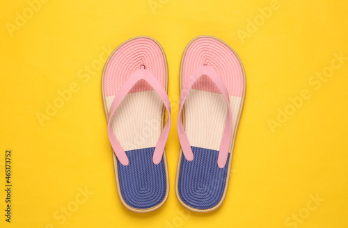 Colored flip flops on yellow background