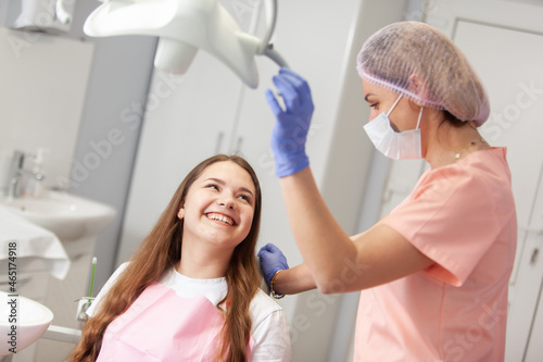 Young European woman being examined by the stomatologist. Beauty woman sitting in medical chair while dentist fixing her teeth at dental clinic. Dentist examining patient s teeth