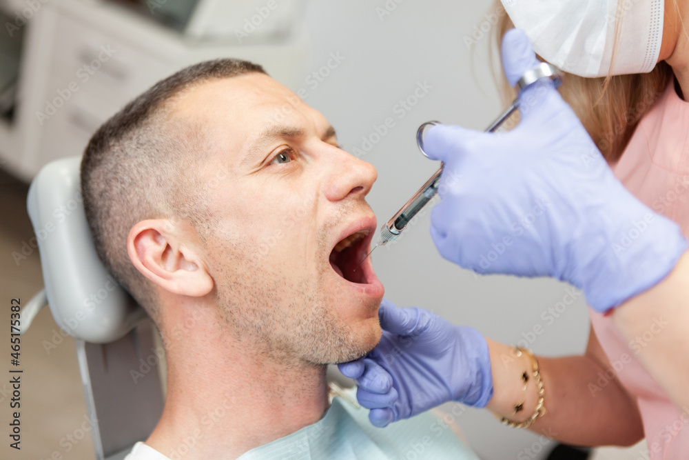 Dentist prick anesthesia to man patient in dental clinic. Dental treatment concept Dentist prick anesthesia to man patient in dental clinic. Dental treatment concept