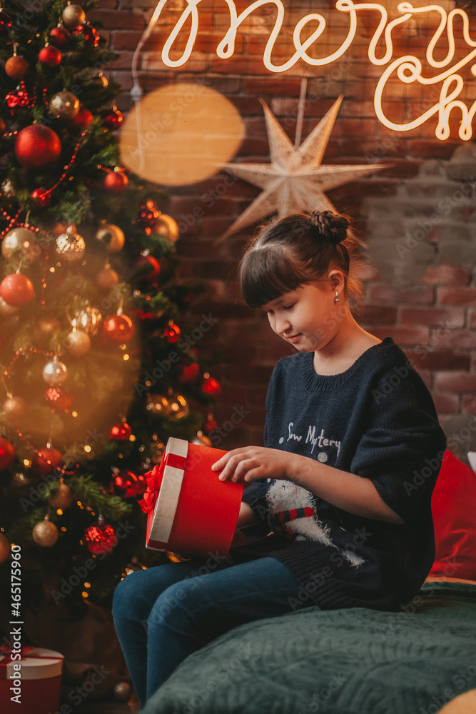 © Татьяна Добрикова - girl opening her gift near christmas tree © Татьяна Добрикова - girl opening her gift near christmas tree
