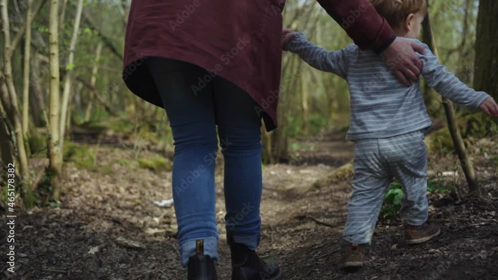 Mother and toddler boy walk through forest, mother guides toddler Mother and toddler boy walk through forest, mother guides toddler