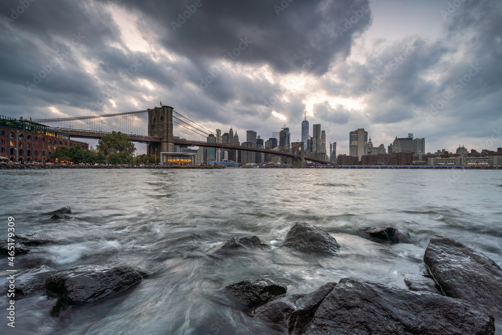 Obraz premium Brooklyn Bridge and Manhattan skyline along the East River on a cloudy day, New York City, USA