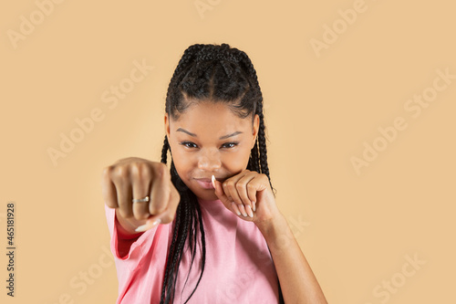 pretty latin woman makes fist gesture on yellow background
