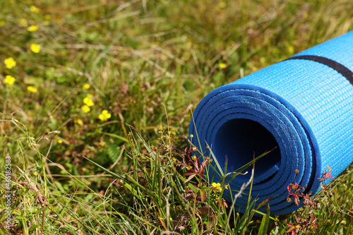 Rolled blue soft sleeping pad on grass, closeup