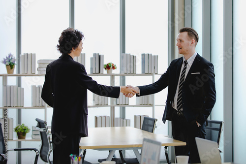 Young caucasian executive business woman delightfully shaking hand with colleauge manager as happy on great negotiation deal and conference agreement for corporation success at company meeting