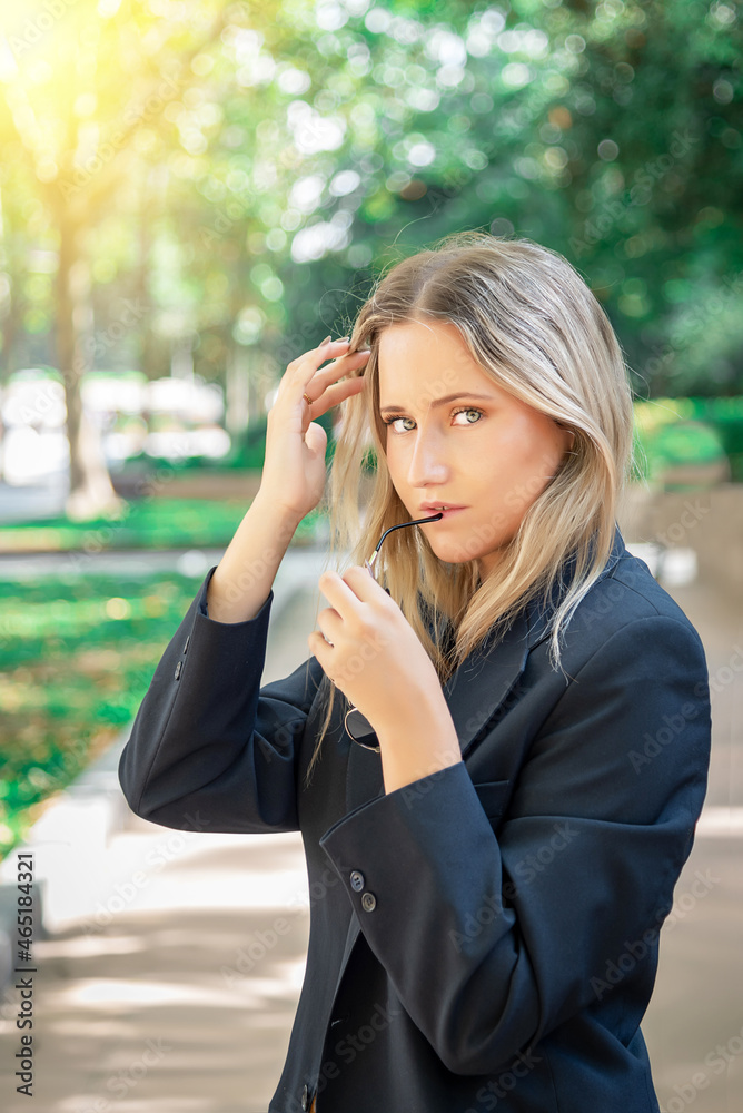 Beautiful light-eyed blonde woman touching her hair, looking at the camera and biting her glasses. Beautiful light-eyed blonde woman touching her hair, looking at the camera and biting her glasses.