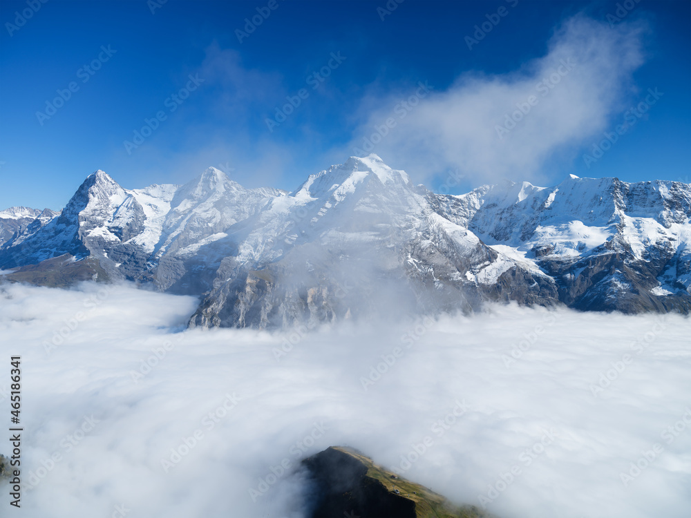 Mountains and clouds in the valley. Natural landscape high in the mountains. Mountain range through the clouds. Landscape in the summertime. Large resolution photo for design.
