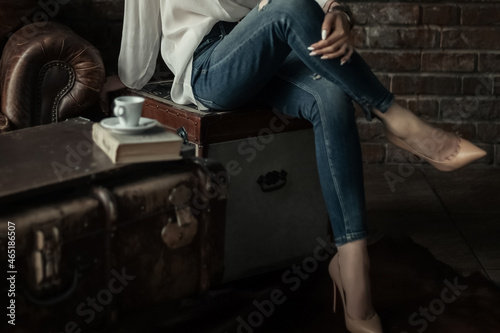 Schilderij op canvas Elegant woman in slim blue jeans sitting with her legs crossed