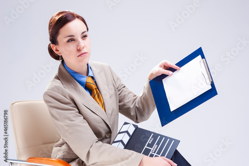 Filmmaking Concepts. Portrait of Young Caucasian Female Posing in Bright Beige Blazer in Chair with Actioncut Indoors. photo