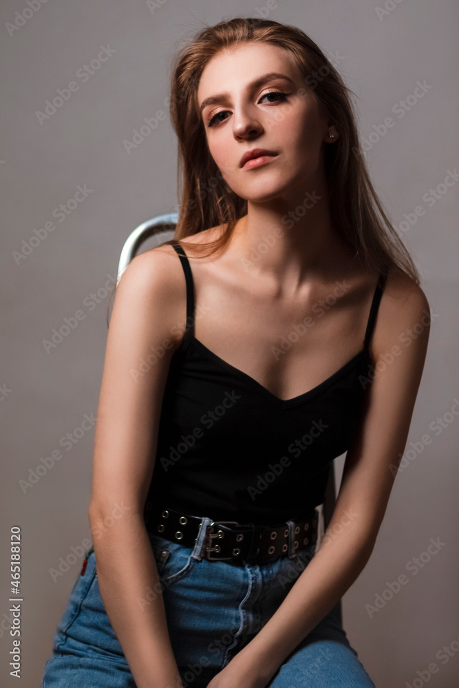 Alluring Caucasian Blond Girl With Long Beautiful Hair Posing on Ladder in Studio Against Dark Background.