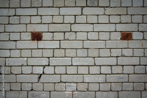 Painted in grey white colors old vintage empty brick wall background with copy space. Rustic cemented house stonewall texture with grunge surface. Shabby Building Facade With Damaged Plaster