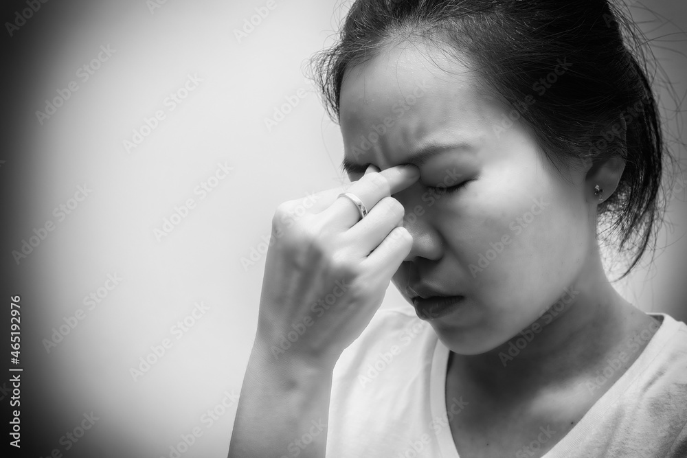 Asian woman with white t-shirt squeezes her eyebrows because headache, flu, COVID 19 or stress. Healthcare concept. Black and white tone Asian woman with white t-shirt squeezes her eyebrows because headache, flu, COVID 19 or stress. Healthcare concept. Black and white tone