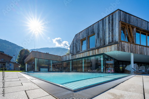 modern pool building with weathered wood facade with fresh turquoise water and sunbeams © A2LE