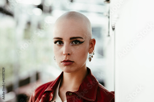 Young bald woman by wall