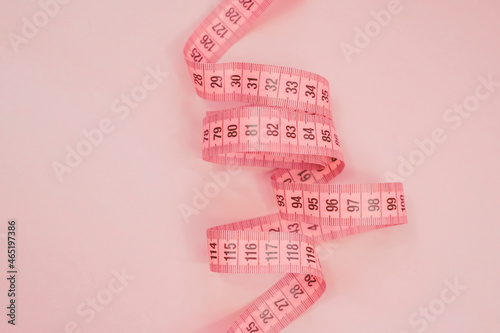 Measure tape on the pastel pink background. Mock up for body slimming, weight loss or dressmaker's offer or other ideas. Empty place for text, logo or object photo