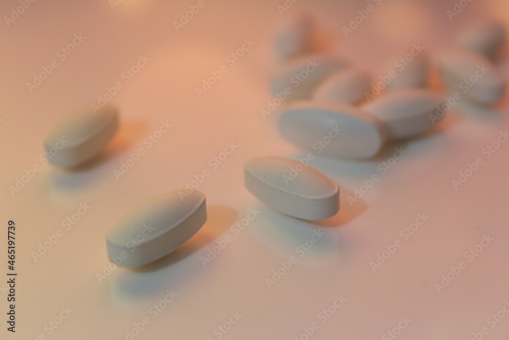 white tablet pills on white blurred background, selective focus