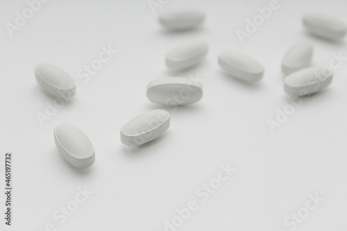 white tablet pills on white blurred background, selective focus