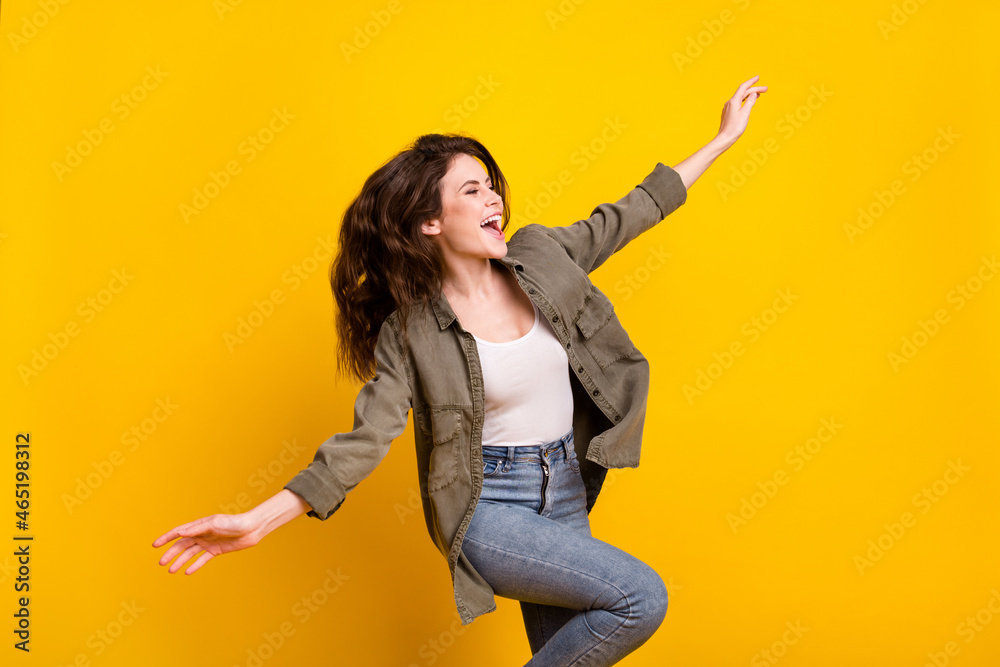 Portrait of attractive cheerful girl dancing having fun good mood freedom isolated over bright yellow color background