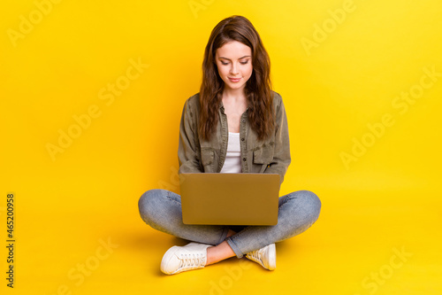 Photo of pretty adorable young woman dressed brown shirt sitting floor typing modern device isolated yellow color background