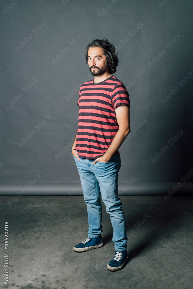 Mid adult man standing with hands in pockets by gray backdrop Mid adult man standing with hands in pockets by gray backdrop