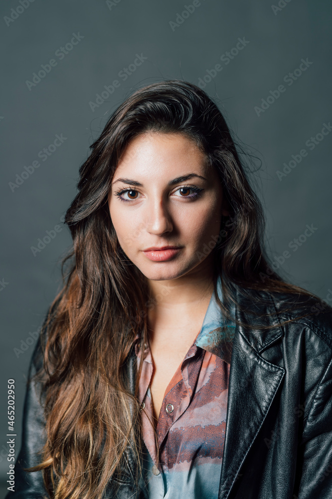 Young woman wearing leather jacket against gray background