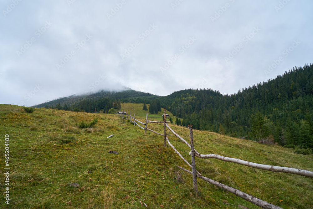 Wooden fence for cattle in the mountains. Mountain foggy background