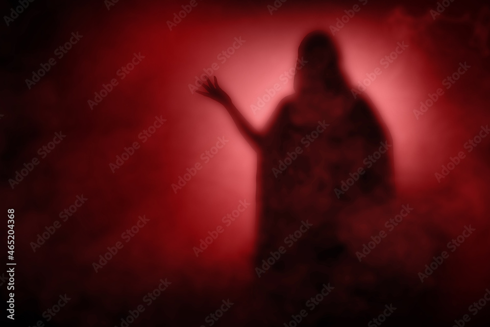 Silhouette of witch woman with a cloak standing