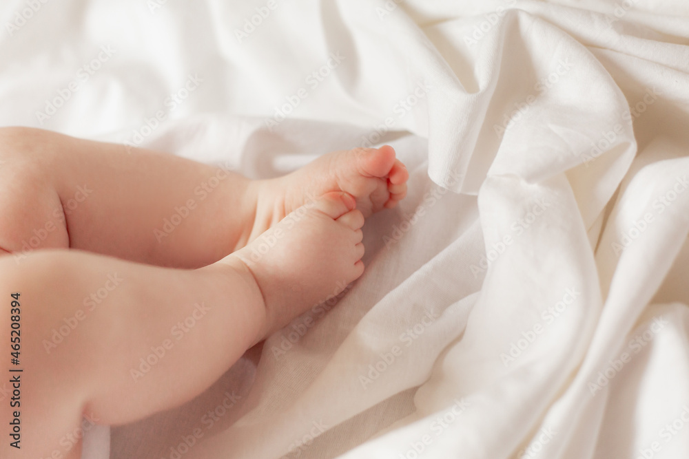 closeup bare children's feet of baby lying on a bed covered with a white sheet made of natural fabric. products for children. concept of happy childhood and motherhood. child care. space for text closeup bare children's feet of baby lying on a bed covered with a white sheet made of natural fabric. products for children. concept of happy childhood and motherhood. child care. space for text