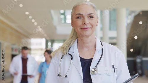 Proud senior doctor walking in hospital hallway