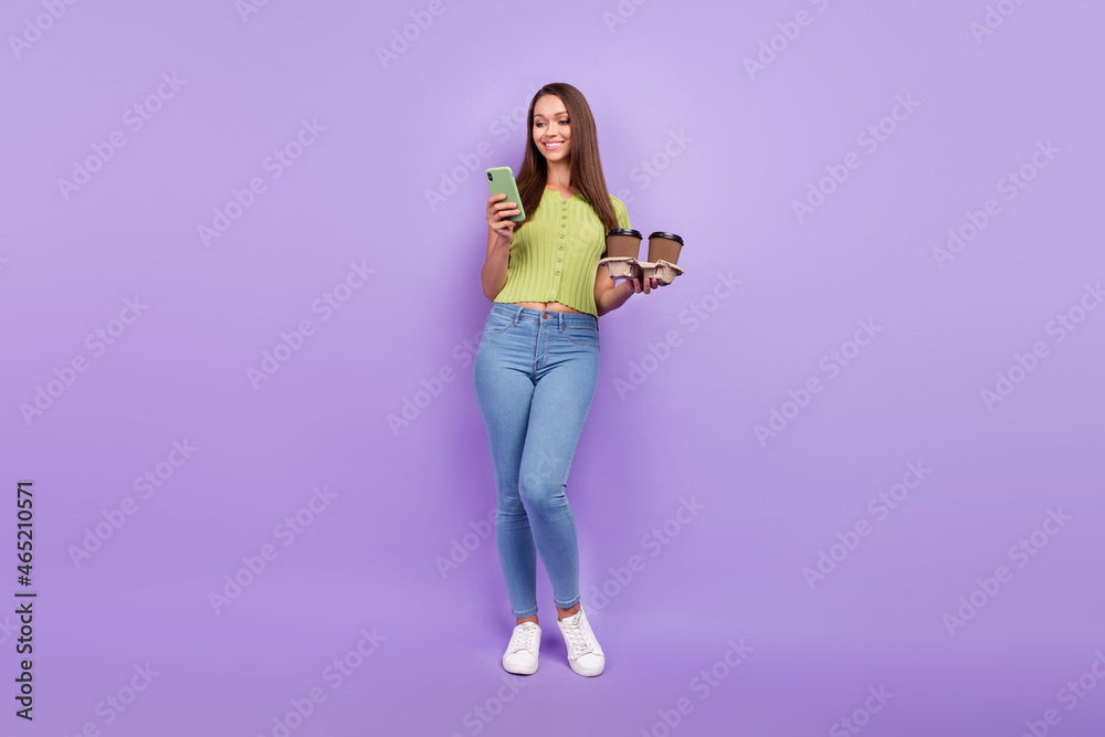 Full length body size view of pretty cheerful girl using device blogging holding latte isolated over purple violet color background Full length body size view of pretty cheerful girl using device blogging holding latte isolated over purple violet color background