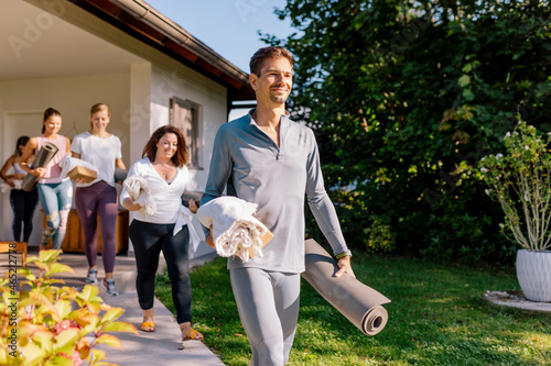 Man and women walking on footpath by house while going to yoga class photo