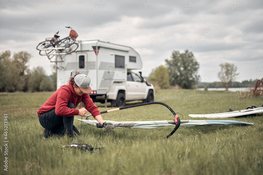Windsurfer and camper packing and unpacking from a car in nature. Windsurfer and camper packing and unpacking from a car in nature.