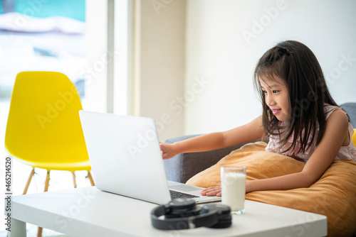 Asian girl homeschooling with laptop computer and online learning at home wile coronavirus or covid-19 outbreak situation. Homeschooling, home study or online learning concept